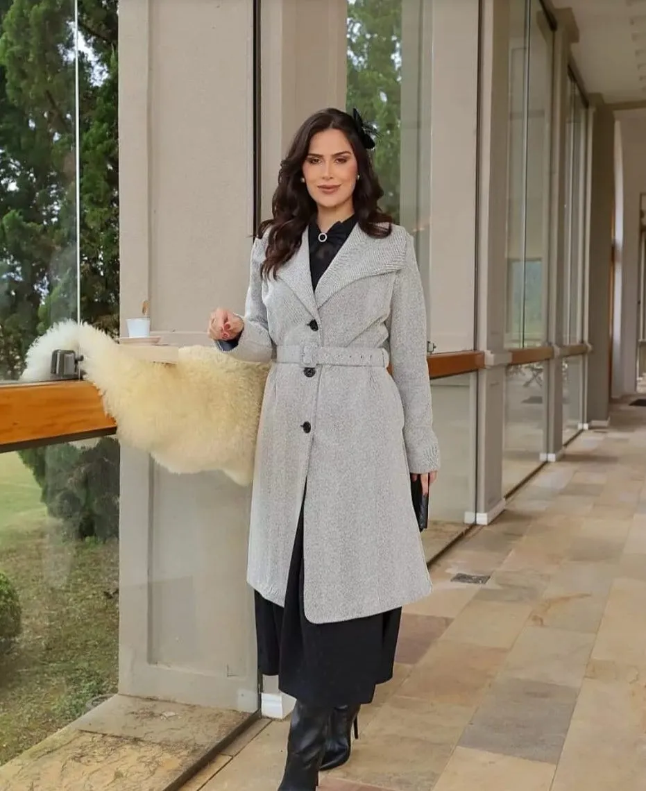 Modelo veste casaco comprido cinzento em tecido tipo tweed, com gola de lapela e cinto