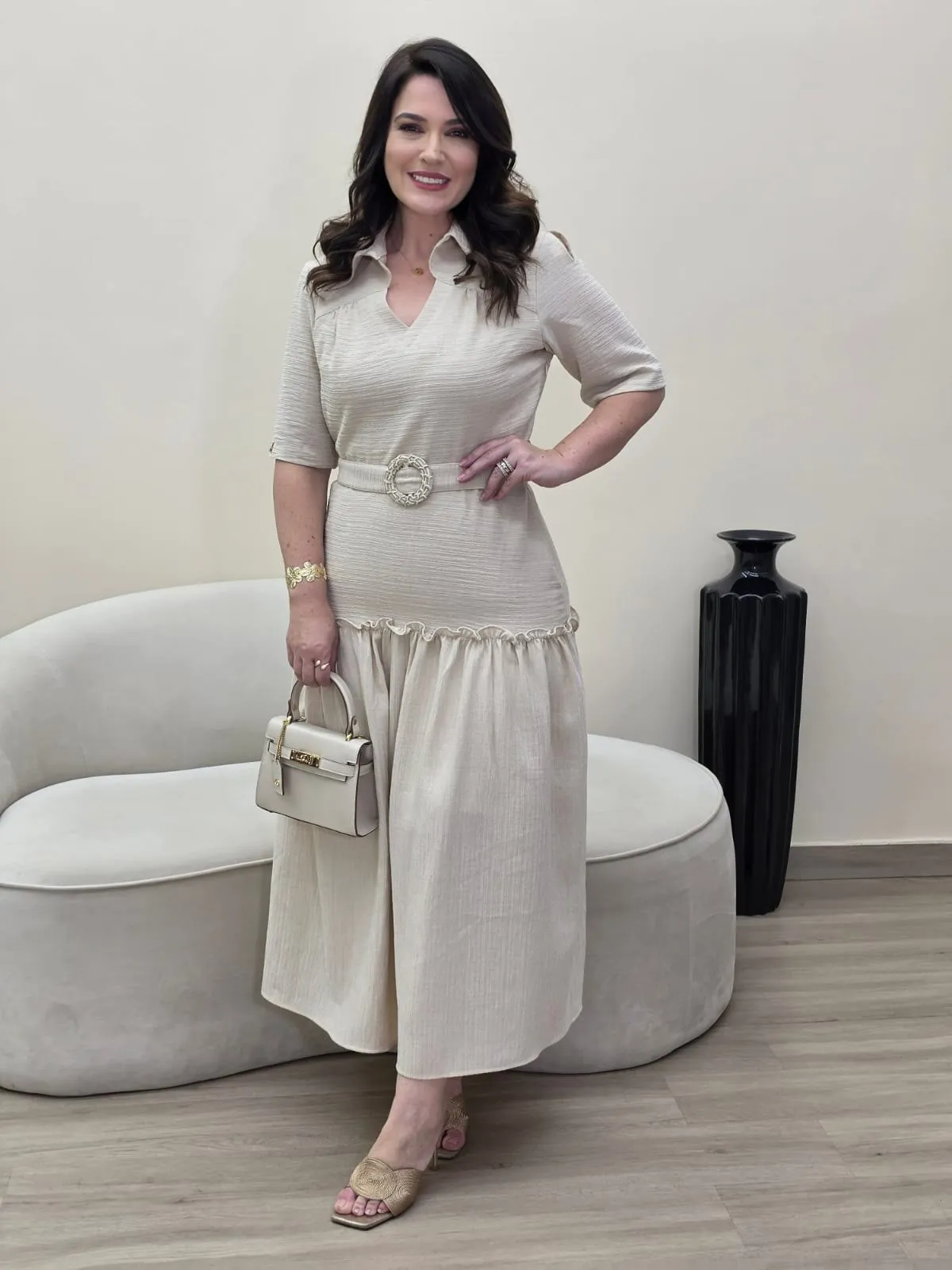 Modelo veste conjunto creme de blusa com gola e saia comprida com folho na barra