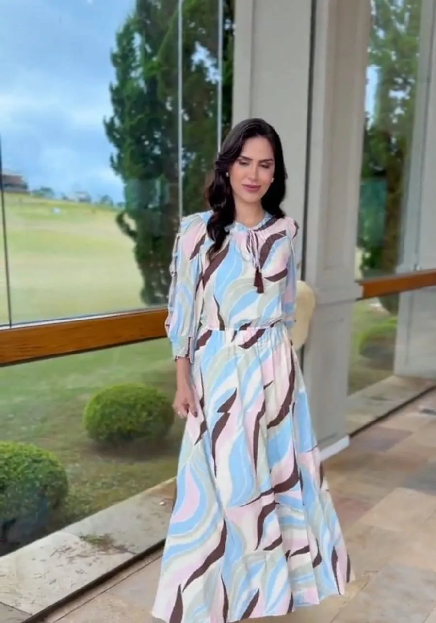 Modelo veste conjunto de blusa e saia comprida com estampado ondulado em tons de azul e rosa