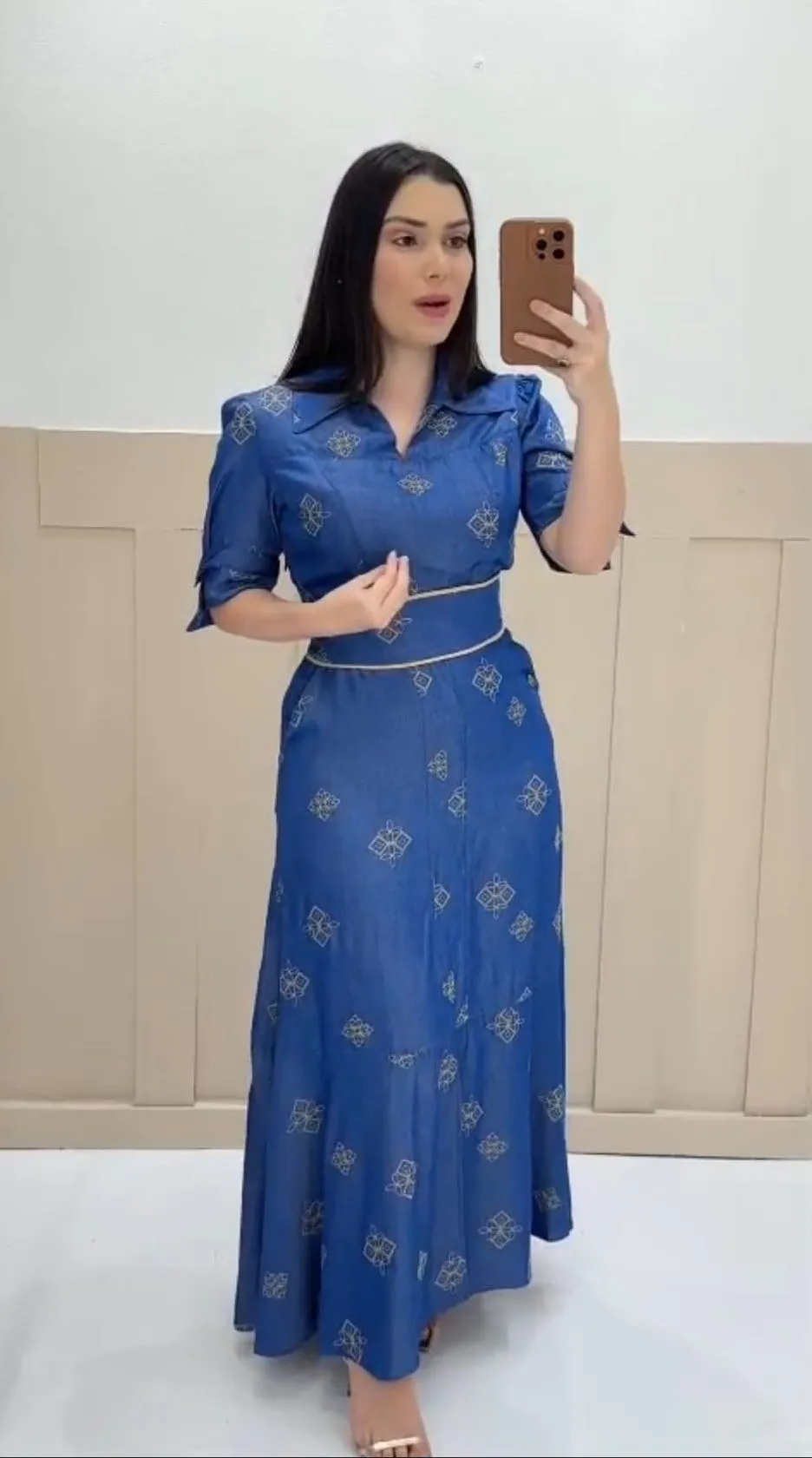 Modelo veste vestido comprido azul com pequenos motivos bordados, colarinho e manga três-quartos
