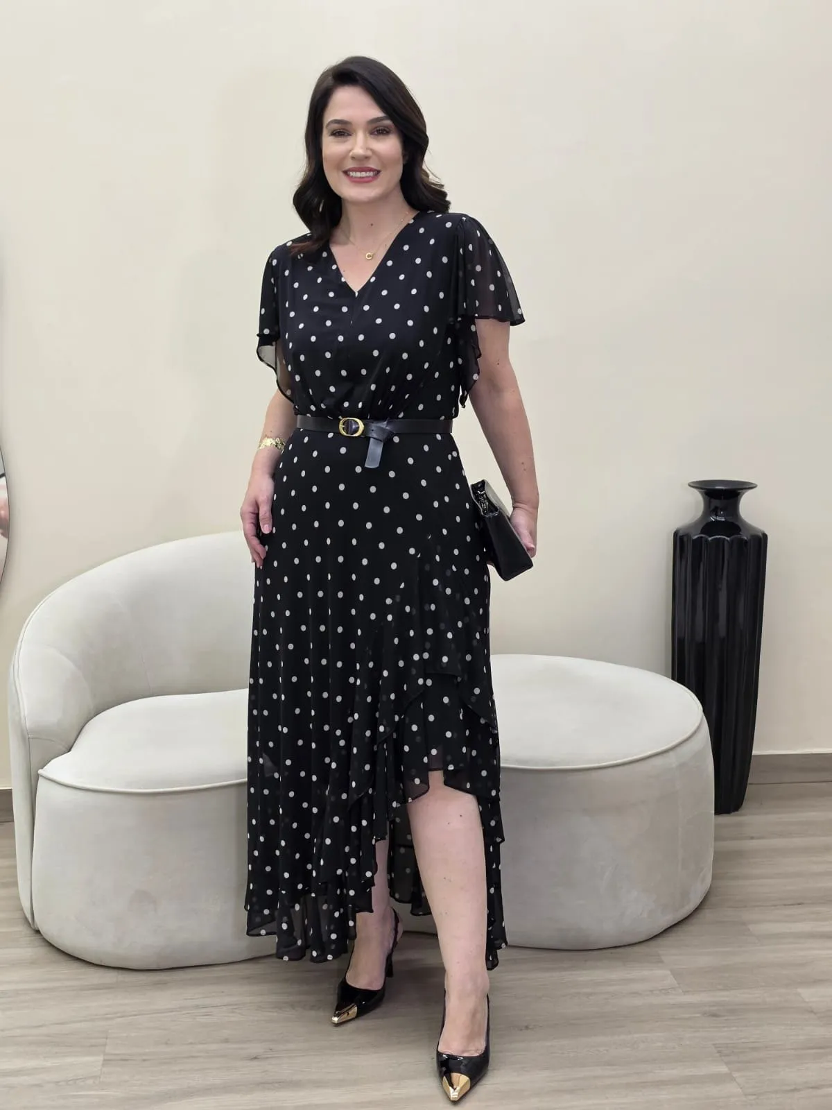 Vestido comprido preto com poá branco, decote em V, mangas curtas soltas e barra assimétrica