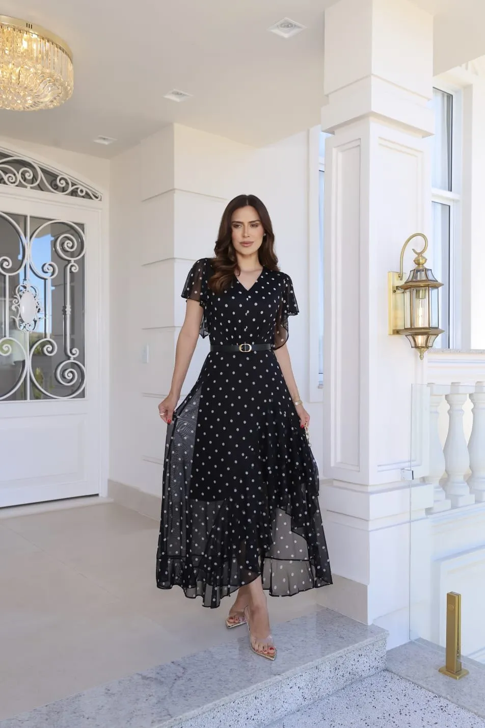 Vestido comprido preto com poá branco, decote em V, mangas curtas soltas e barra assimétrica